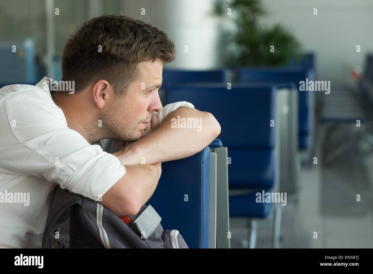 Jungen kaukasischen Mann am Flughafen und wartet auf seine Ebene betrachten die windoe Stockfoto