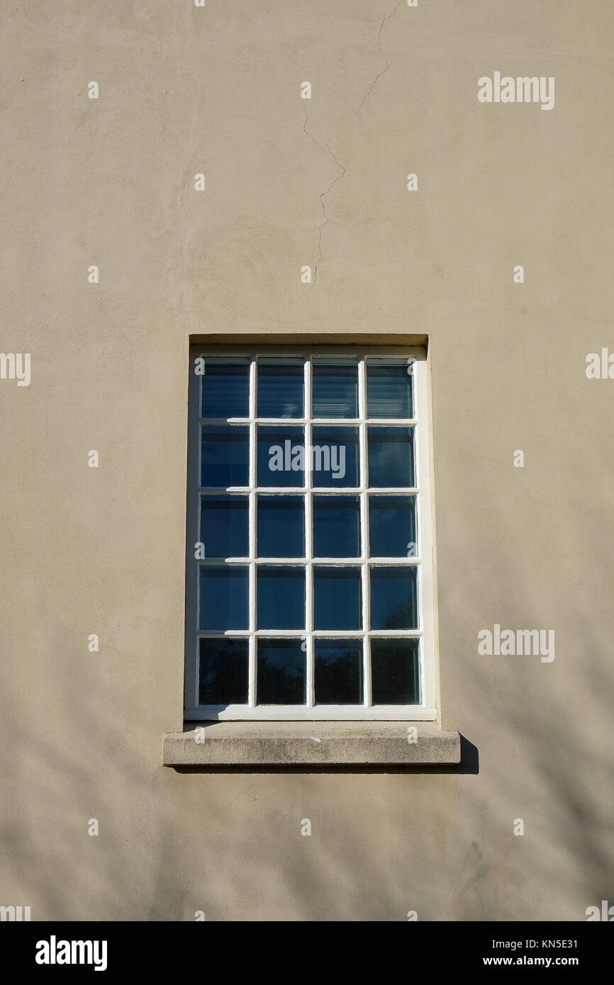 Big Square Fenster mit kleinen Verglasung Muster aus vielen haust in einer verputzten Fassade Stockfoto