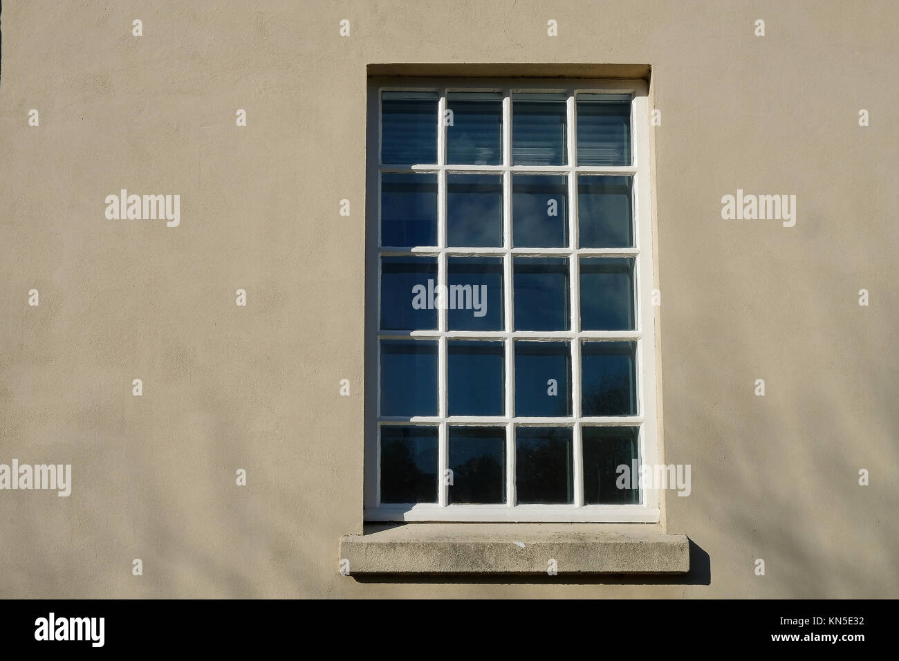 Big Square Fenster mit kleinen Verglasung Muster aus vielen haust in einer verputzten Fassade Stockfoto