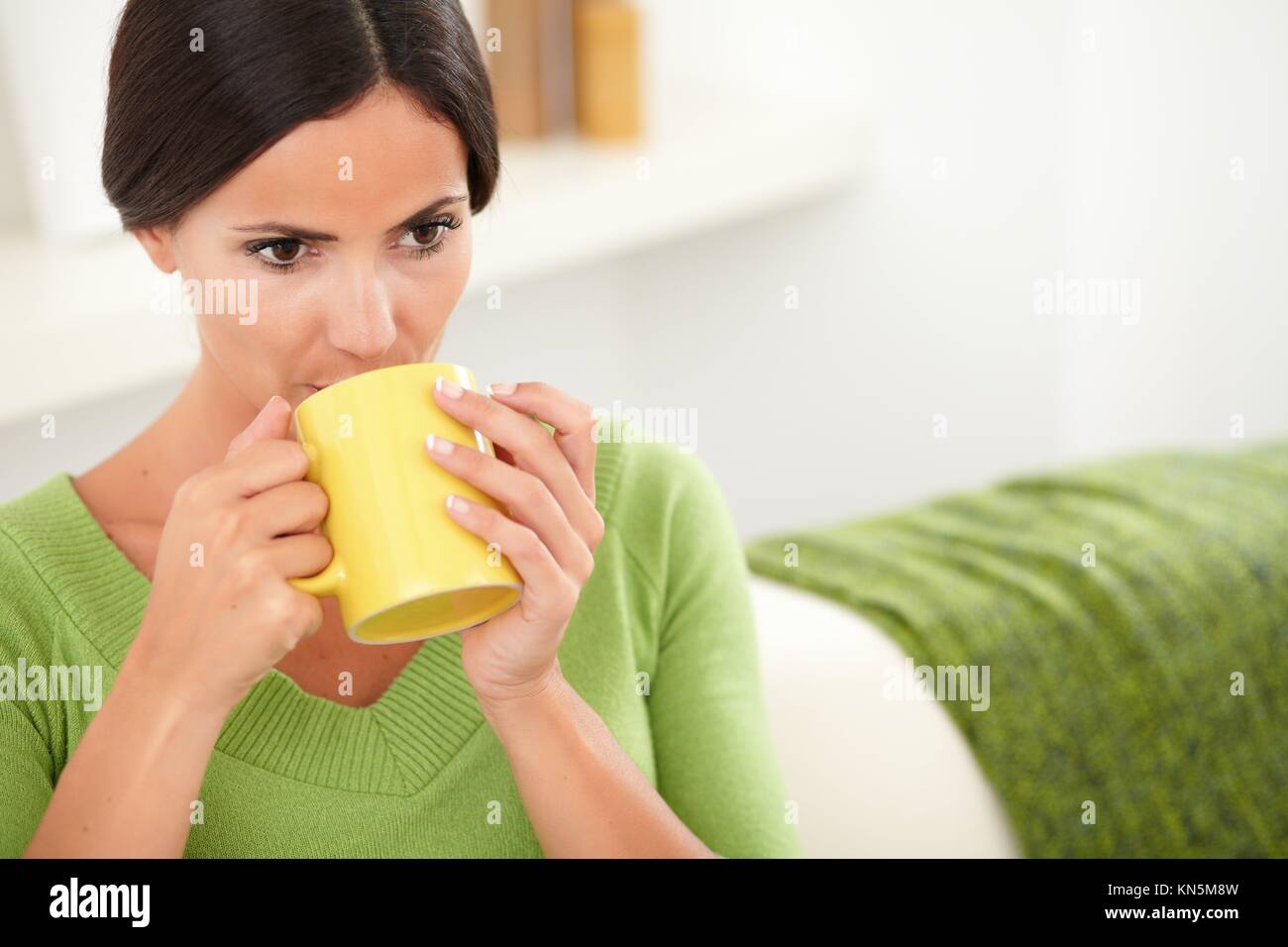 Kaukasische Frau mit geradem Haar trinken Ihren täglichen Kaffee im Innenbereich. Stockfoto