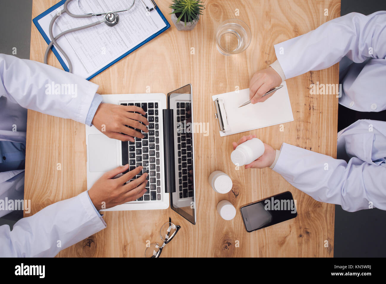 Medizin, Gesundheitswesen und Kardiologie Konzept - Gruppe von Ärzten mit Elektrokardiogramm, Zwischenablage, Tablet-pcs und Laptops im Krankenhaus Stockfoto