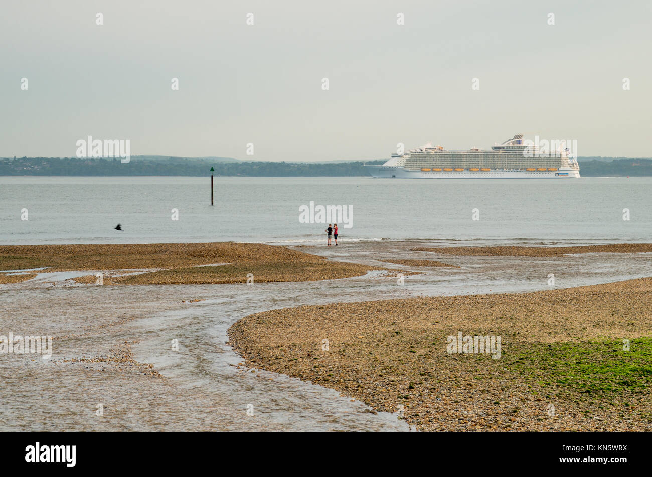 Eine Szene in Stokes Bay mit einem großen Kreuzfahrtschiff vorbei und zwei Kinder am Ufer beobachten. Ein großer Strom, der den Strand ins Meer. Stockfoto