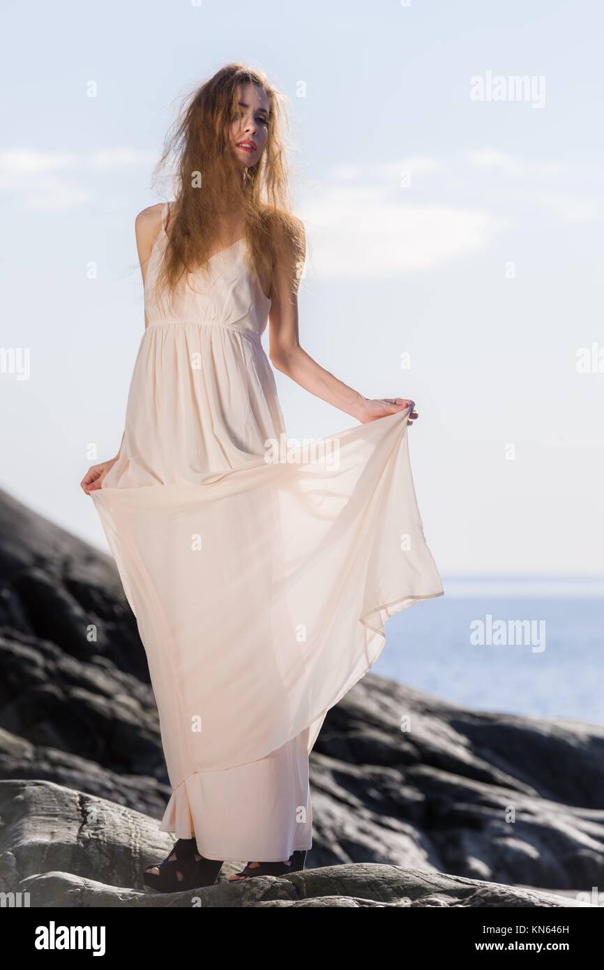 Schöne junge Frau in weißem Kleid, skandinavische Land und Meer im Hintergrund. Stockfoto