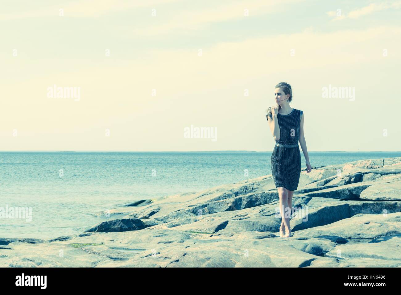 Modische Frau Wandern auf dem felsigen Ufer, der Horizont für den Hintergrund. Stockfoto