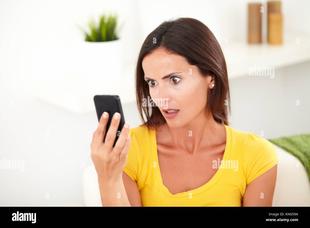 Kopf und Schultern Porträt einer Frau auf der Suche schockiert auf Ihrem Mobiltelefon - Fokus auf den Vordergrund. Stockfoto