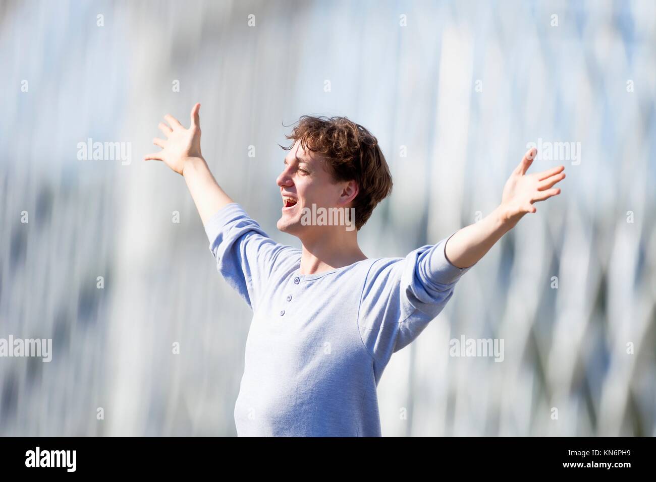 Aufgeregt junger Mann streckte seinen Arm in Emotion im Freien. Stockfoto