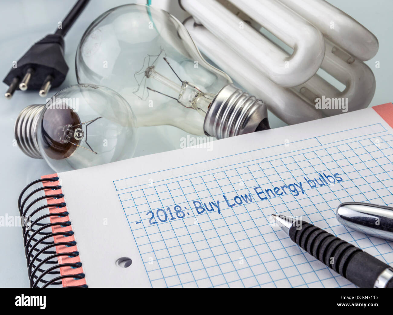 Taschenrechner und Geld neben einer Glühbirne, schreiben in der Agenda 2018 die Glühlampen der niedrige Verbrauch kaufen, das Konzept der Energieeinsparung Stockfoto