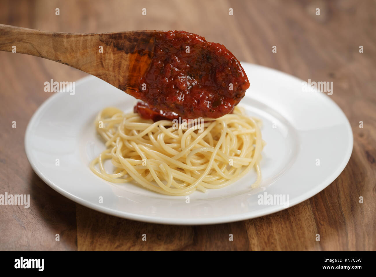 Auf Spaghetti Bolognese Sauce hinzufügen, flacher Fokus Stockfoto