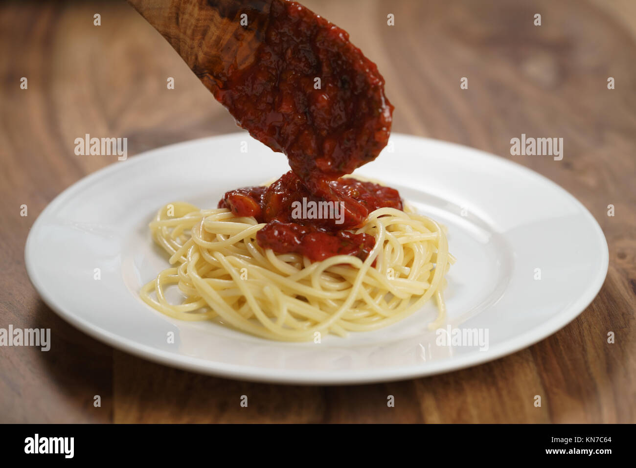 Auf Spaghetti Bolognese Sauce hinzufügen, flacher Fokus Stockfoto