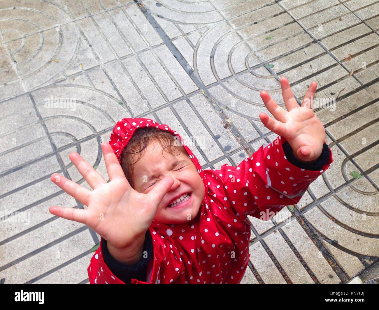 Hübsches kleines Mädchen Spaß haben einen Regen Tag auf der Straße. Stockfoto