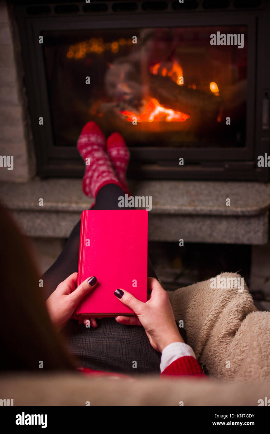 Mädchen lesen durch das Feuer. Gemütliche winter Lifestyle im Innenbereich Stockfoto