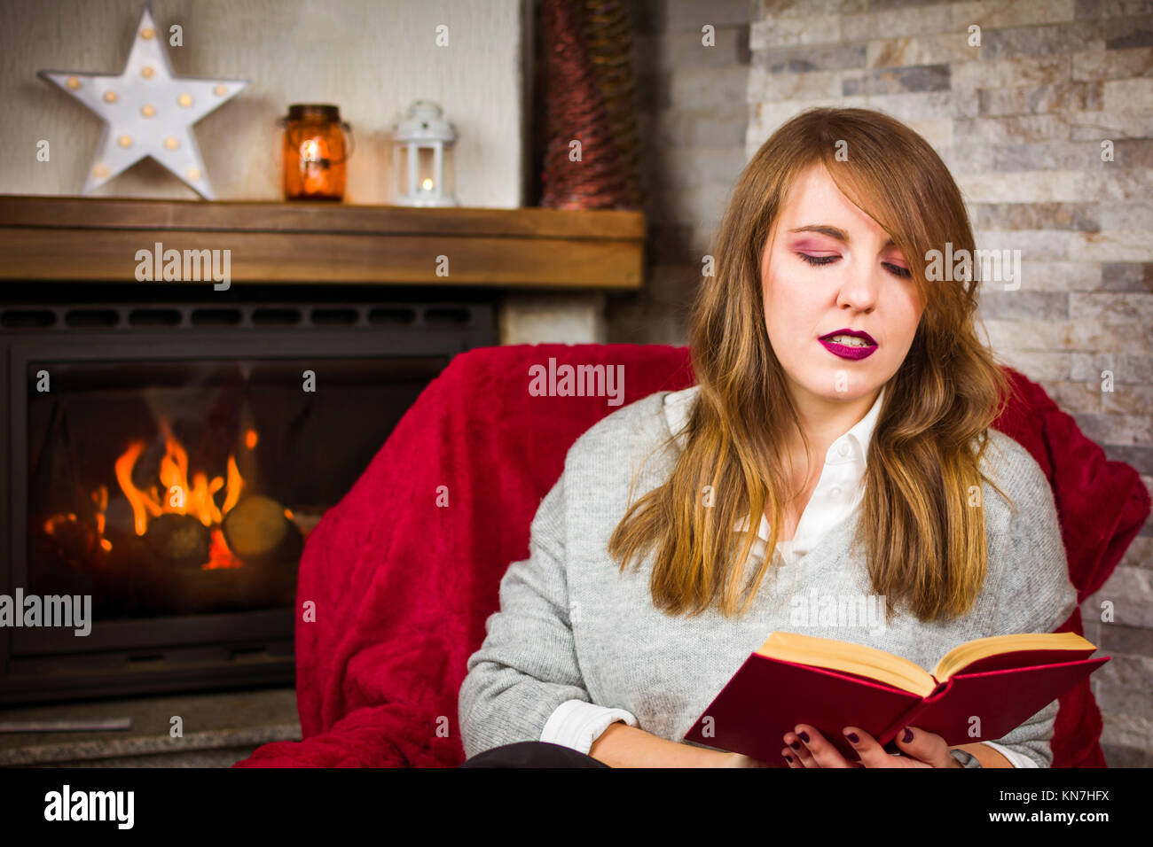 Frau mit einem Buch am Kamin, winter Lifestyle Stockfoto