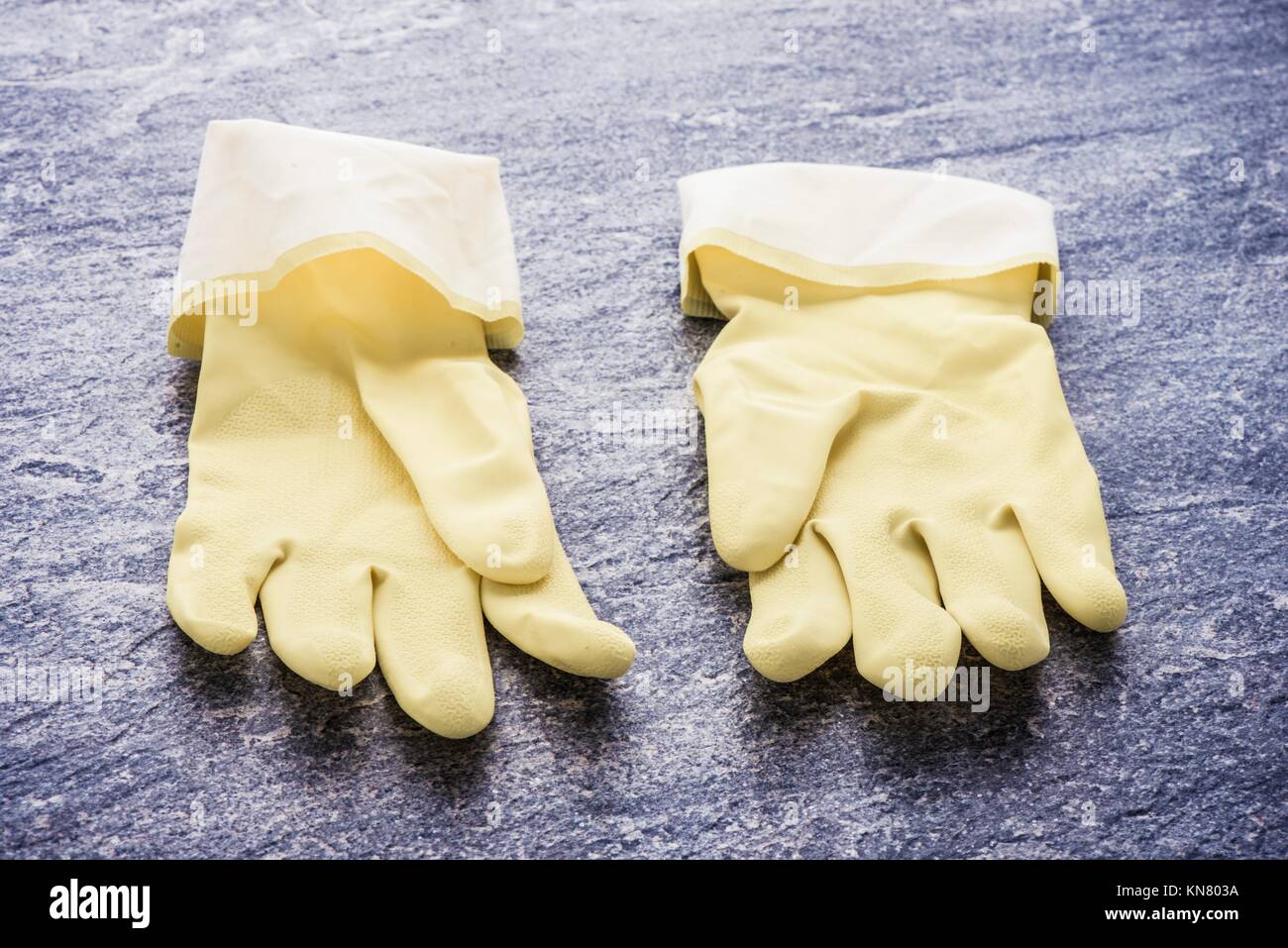 Gelbe Gummihandschuhe liegen auf Stein Oberfläche. Image an, das Konzept der Reinigung, Hausarbeit und Schutzkleidung. Stockfoto
