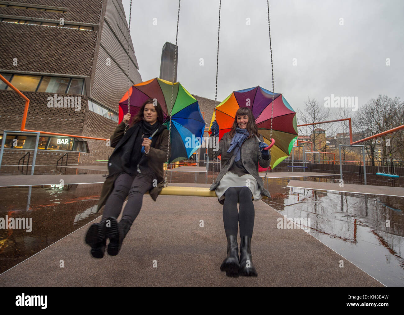 Tate Modern, London, UK. 11. Dezember, 2017. Elf schaukeln müssen außerhalb der Galerie Blavatnik Gebäude installiert wurde, als Teil einer groß angelegten interaktive Installation von Dänischen kollektiv SUPERFLEX. Eins, Zwei, Drei! Ist die erste Hyundai Kommission über die Turbine Hall zu erweitern und in die Landschaft draußen. Die großen Installation verfügt über elf 3 Sitz schwingt vor dem Hintergrund der legendären Tate Modern Gebäude mit Mitgliedern der lokalen Gemeinschaft genießen die Schaukeln für die erste Zeit im strömenden Regen. Credit: Malcolm Park/Alamy Leben Nachrichten. Stockfoto