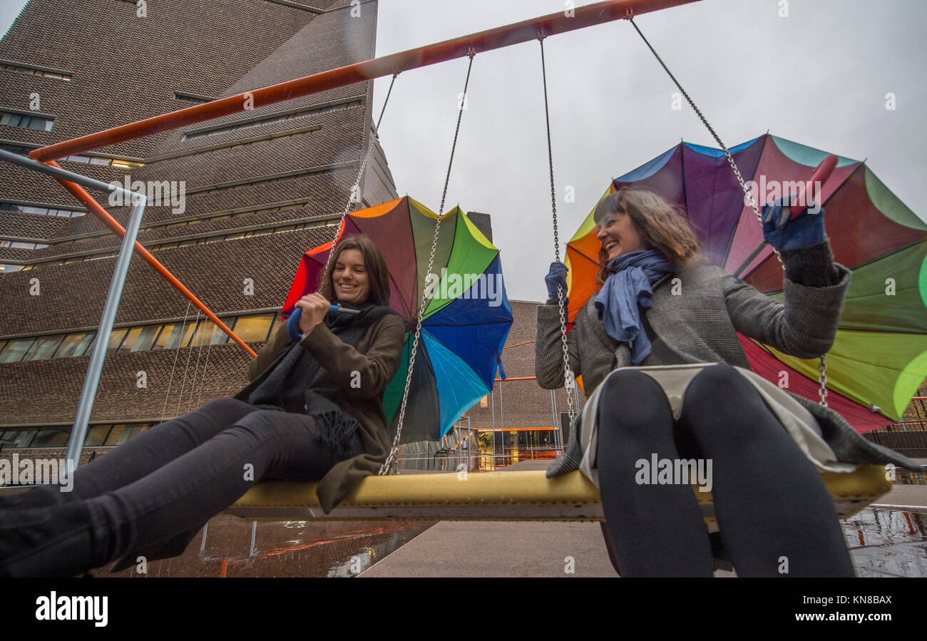 Tate Modern, London, UK. 11. Dezember, 2017. Elf schaukeln müssen außerhalb der Galerie Blavatnik Gebäude installiert wurde, als Teil einer groß angelegten interaktive Installation von Dänischen kollektiv SUPERFLEX. Eins, Zwei, Drei! Ist die erste Hyundai Kommission über die Turbine Hall zu erweitern und in die Landschaft draußen. Die großen Installation verfügt über elf 3 Sitz schwingt vor dem Hintergrund der legendären Tate Modern Gebäude mit Mitgliedern der lokalen Gemeinschaft genießen die Schaukeln für die erste Zeit im strömenden Regen. Credit: Malcolm Park/Alamy Leben Nachrichten. Stockfoto