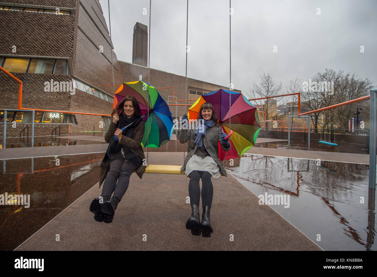 Tate Modern, London, UK. 11. Dezember, 2017. Elf schaukeln müssen außerhalb der Galerie Blavatnik Gebäude installiert wurde, als Teil einer groß angelegten interaktive Installation von Dänischen kollektiv SUPERFLEX. Eins, Zwei, Drei! Ist die erste Hyundai Kommission über die Turbine Hall zu erweitern und in die Landschaft draußen. Die großen Installation verfügt über elf 3 Sitz schwingt vor dem Hintergrund der legendären Tate Modern Gebäude mit Mitgliedern der lokalen Gemeinschaft genießen die Schaukeln für die erste Zeit im strömenden Regen. Credit: Malcolm Park/Alamy Leben Nachrichten. Stockfoto