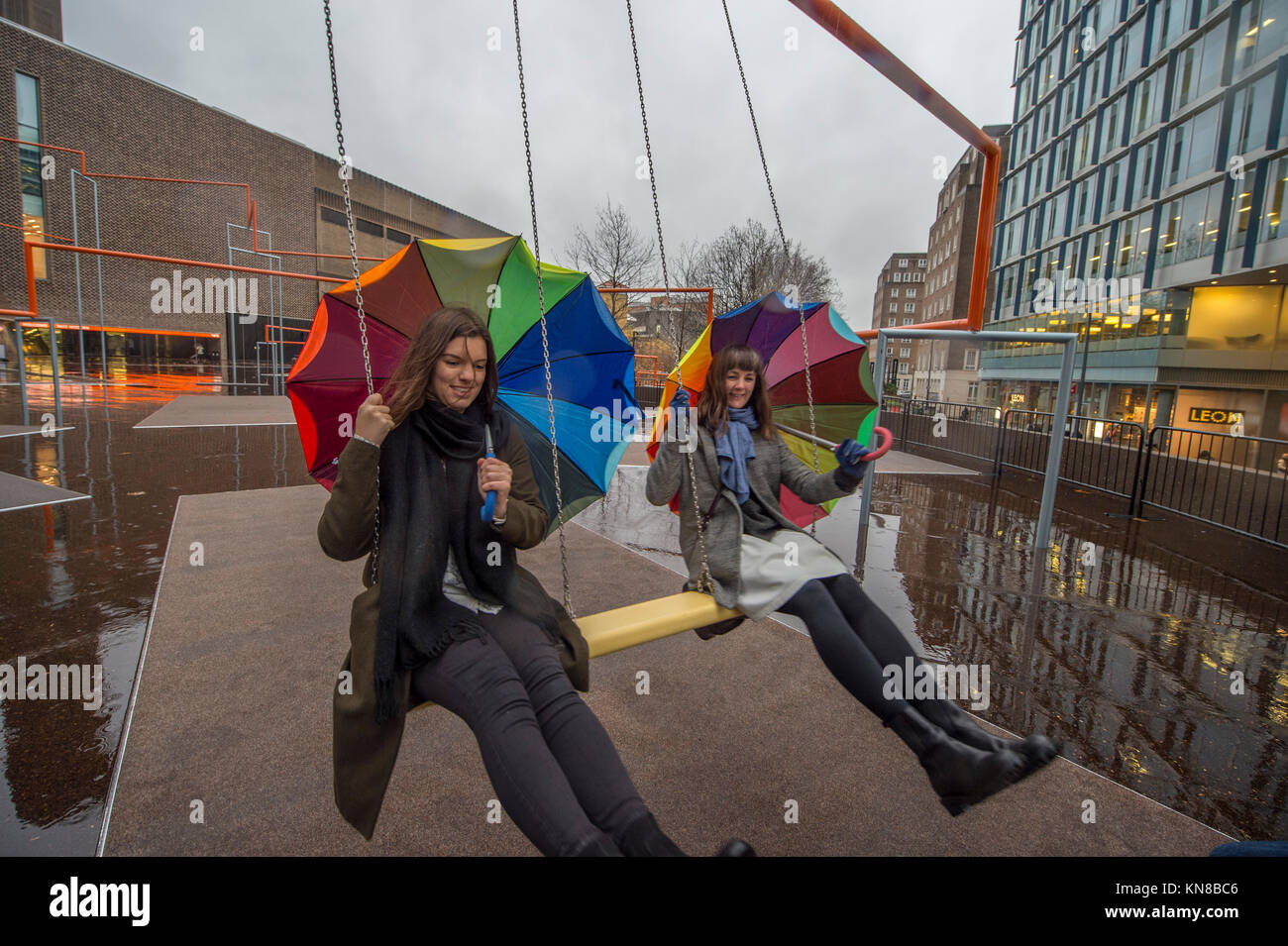 Tate Modern, London, UK. 11. Dezember, 2017. Elf schaukeln müssen außerhalb der Galerie Blavatnik Gebäude installiert wurde, als Teil einer groß angelegten interaktive Installation von Dänischen kollektiv SUPERFLEX. Eins, Zwei, Drei! Ist die erste Hyundai Kommission über die Turbine Hall zu erweitern und in die Landschaft draußen. Die großen Installation verfügt über elf 3 Sitz schwingt vor dem Hintergrund der legendären Tate Modern Gebäude mit Mitgliedern der lokalen Gemeinschaft genießen die Schaukeln für die erste Zeit im strömenden Regen. Credit: Malcolm Park/Alamy Leben Nachrichten. Stockfoto