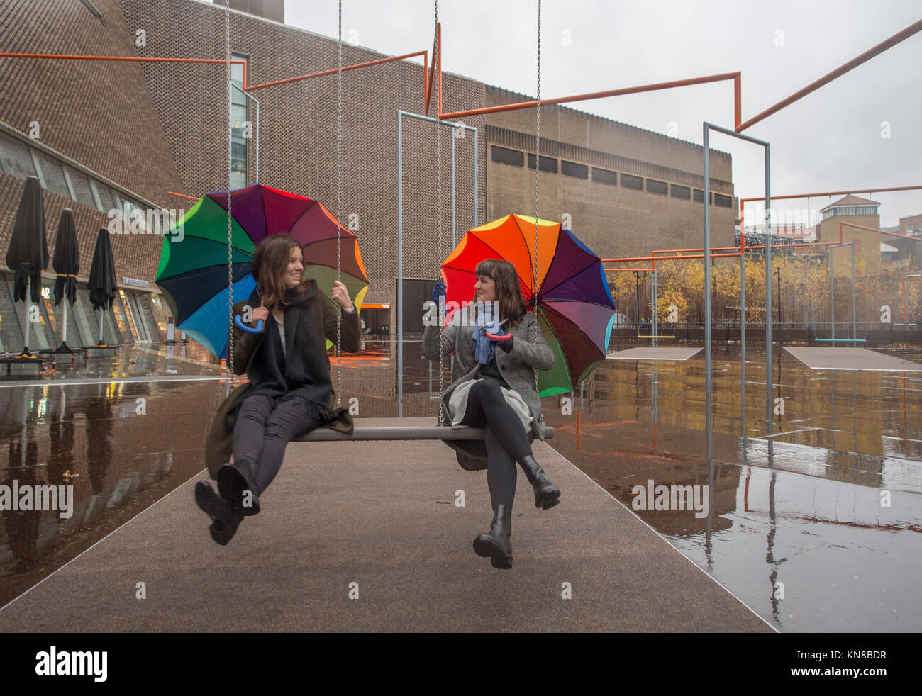 Tate Modern, London, UK. 11. Dezember, 2017. Elf schaukeln müssen außerhalb der Galerie Blavatnik Gebäude installiert wurde, als Teil einer groß angelegten interaktive Installation von Dänischen kollektiv SUPERFLEX. Eins, Zwei, Drei! Ist die erste Hyundai Kommission über die Turbine Hall zu erweitern und in die Landschaft draußen. Die großen Installation verfügt über elf 3 Sitz schwingt vor dem Hintergrund der legendären Tate Modern Gebäude mit Mitgliedern der lokalen Gemeinschaft genießen die Schaukeln für die erste Zeit im strömenden Regen. Credit: Malcolm Park/Alamy Leben Nachrichten. Stockfoto