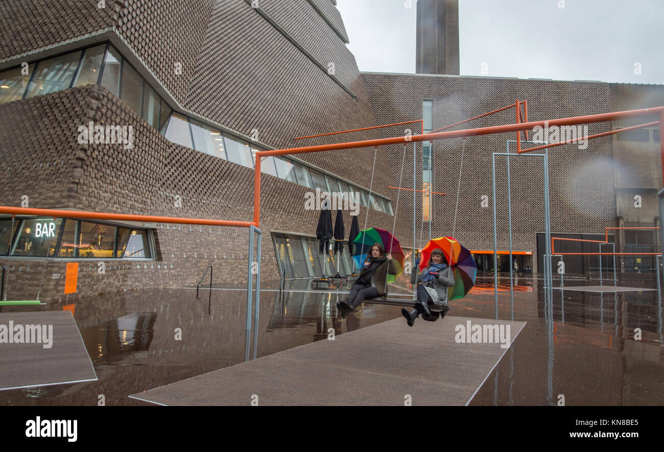Tate Modern, London, UK. 11. Dezember, 2017. Elf schaukeln müssen außerhalb der Galerie Blavatnik Gebäude installiert wurde, als Teil einer groß angelegten interaktive Installation von Dänischen kollektiv SUPERFLEX. Eins, Zwei, Drei! Ist die erste Hyundai Kommission über die Turbine Hall zu erweitern und in die Landschaft draußen. Die großen Installation verfügt über elf 3 Sitz schwingt vor dem Hintergrund der legendären Tate Modern Gebäude mit Mitgliedern der lokalen Gemeinschaft genießen die Schaukeln für die erste Zeit im strömenden Regen. Credit: Malcolm Park/Alamy Leben Nachrichten. Stockfoto