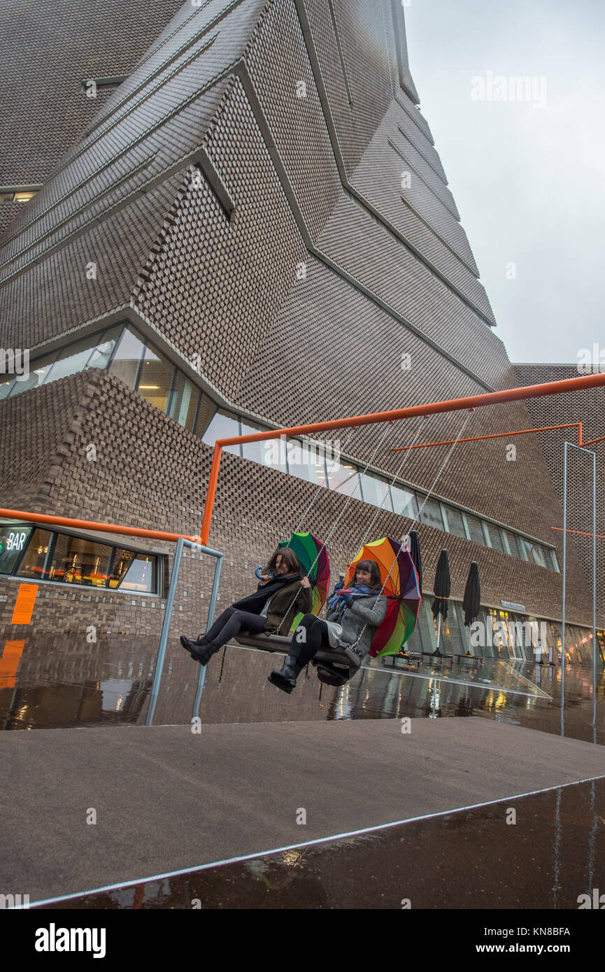 Tate Modern, London, UK. 11. Dezember, 2017. Elf schaukeln müssen außerhalb der Galerie Blavatnik Gebäude installiert wurde, als Teil einer groß angelegten interaktive Installation von Dänischen kollektiv SUPERFLEX. Eins, Zwei, Drei! Ist die erste Hyundai Kommission über die Turbine Hall zu erweitern und in die Landschaft draußen. Die großen Installation verfügt über elf 3 Sitz schwingt vor dem Hintergrund der legendären Tate Modern Gebäude mit Mitgliedern der lokalen Gemeinschaft genießen die Schaukeln für die erste Zeit im strömenden Regen. Credit: Malcolm Park/Alamy Leben Nachrichten. Stockfoto