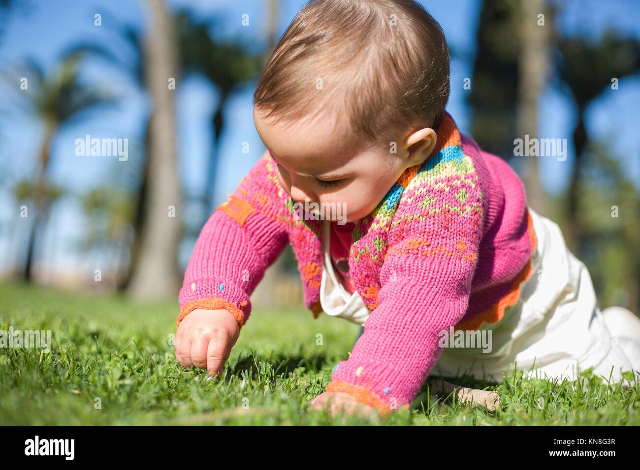 Cute Baby Mädchen lernen über das Gras Park auf Frühling zu kriechen. Stockfoto