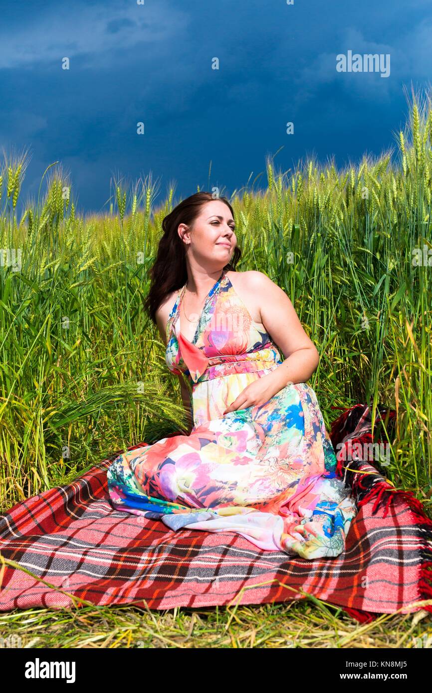 Frau sitzt auf der Plaid im Roggen Feld mit blauem Himmel. Stockfoto