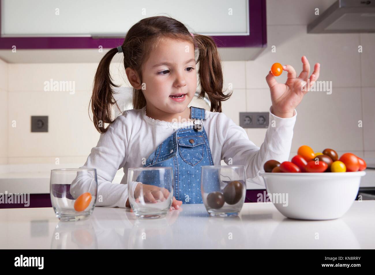 Kleines Mädchen Sortierung nach Farben Cherry Tomaten. Aufklärung über gesunde Ernährung für Kinder. Stockfoto