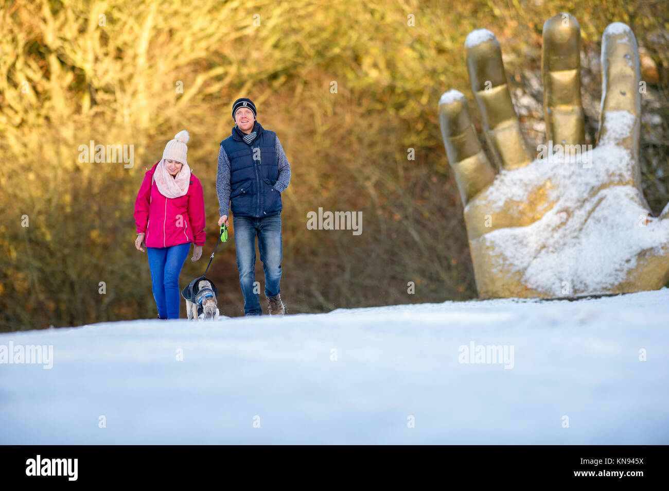 Paar mit einem jungen Whippet Hund mit der goldenen Hand Skulptur in der backgroung. Stockfoto