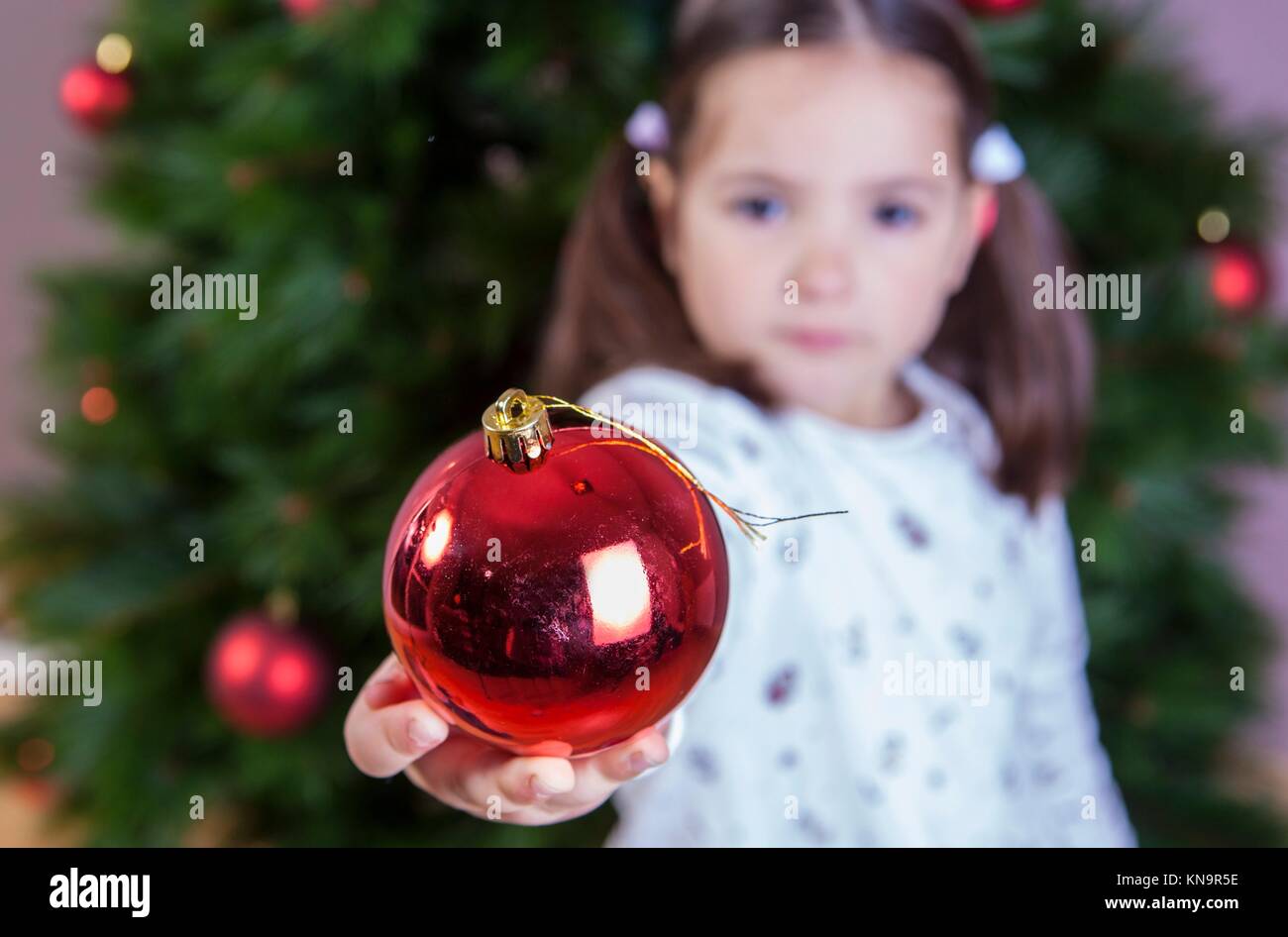 Kleines Mädchen zeigt eine Kugel für Xmas Tree Dekoration. Stockfoto