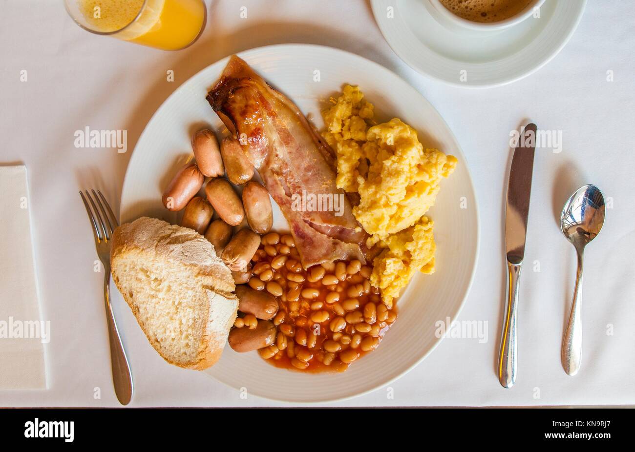 Nahrhaftes englisches Frühstück auf einem Teller mit Brot, Orangensaft und Kaffee Tasse. Stockfoto