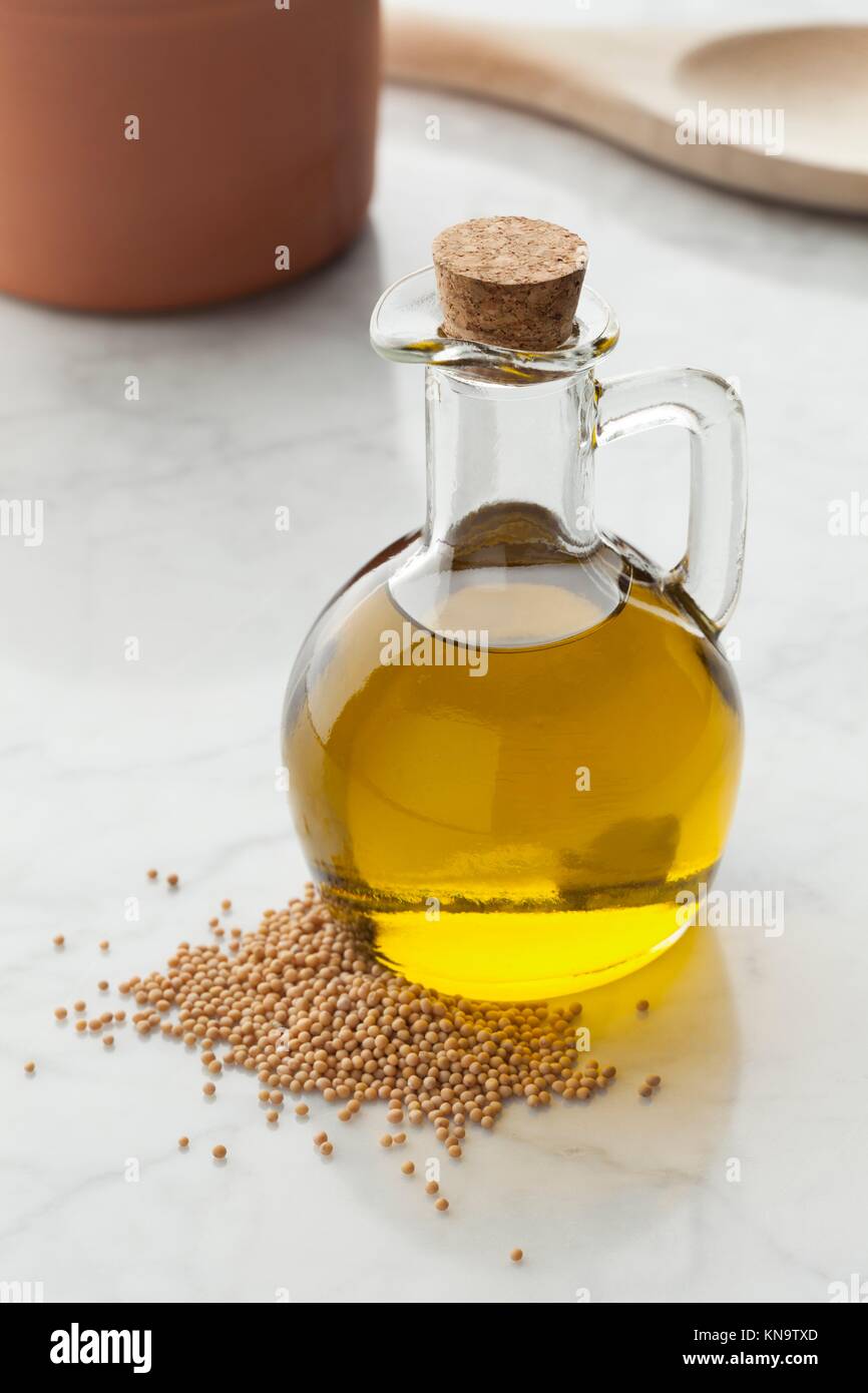 Glasflasche mit Senföl und einem Haufen Samen. Stockfoto
