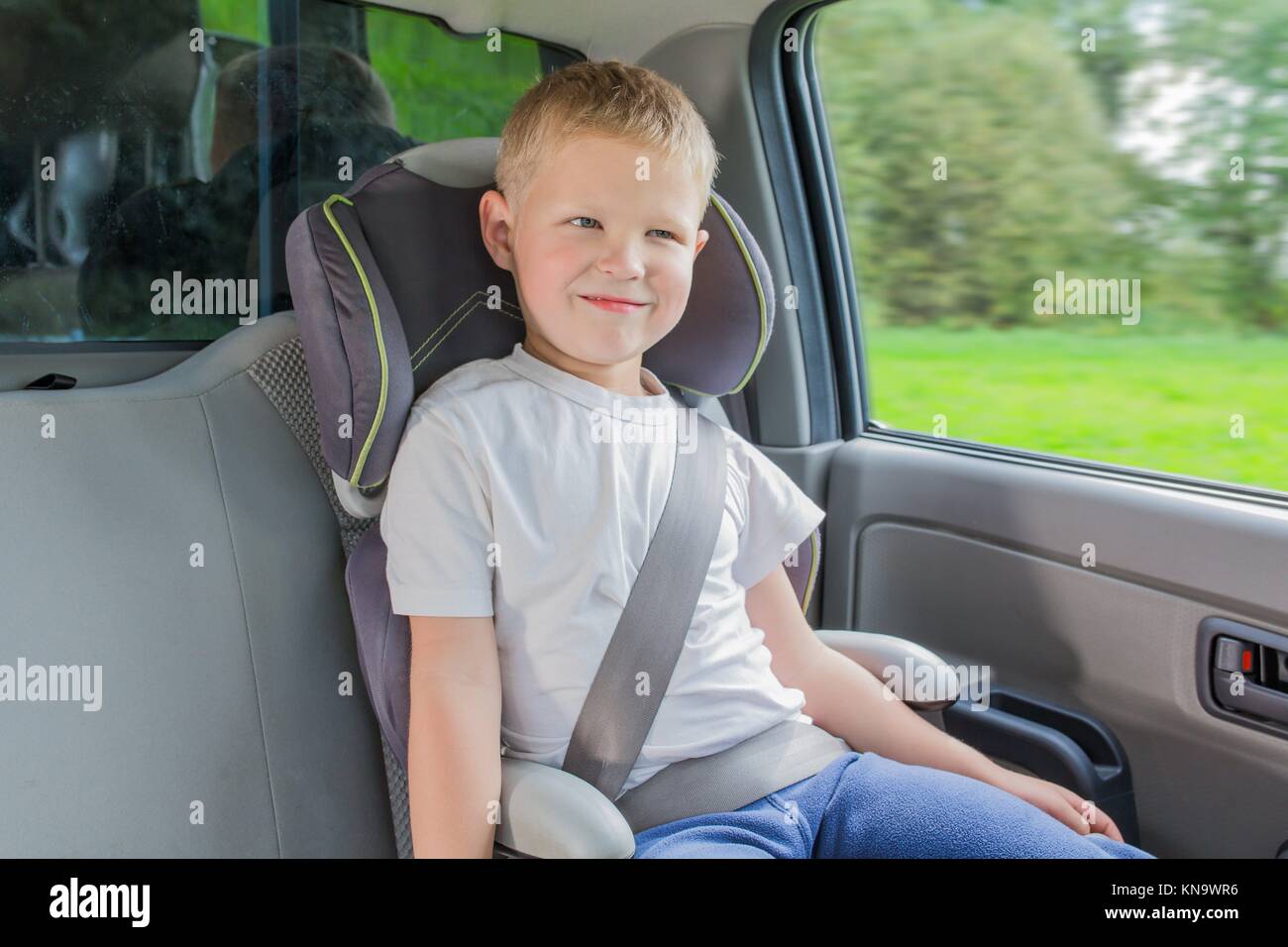 Junge sitzt in einem Auto in Sicherheit Stuhl befestigen, indem