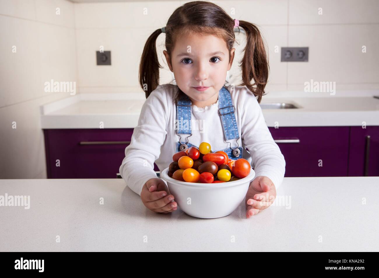 Kleines Mädchen mit Kirschtomaten Schüssel. Aufklärung über gesunde Ernährung für Kinder. Stockfoto
