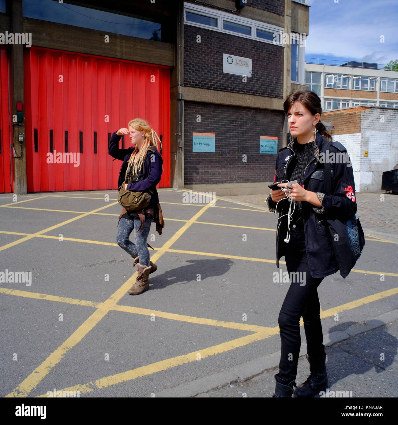 Junge Frauen gehen früher Eingang der Feuerwache in Shoreditch, London, England, Großbritannien Stockfoto