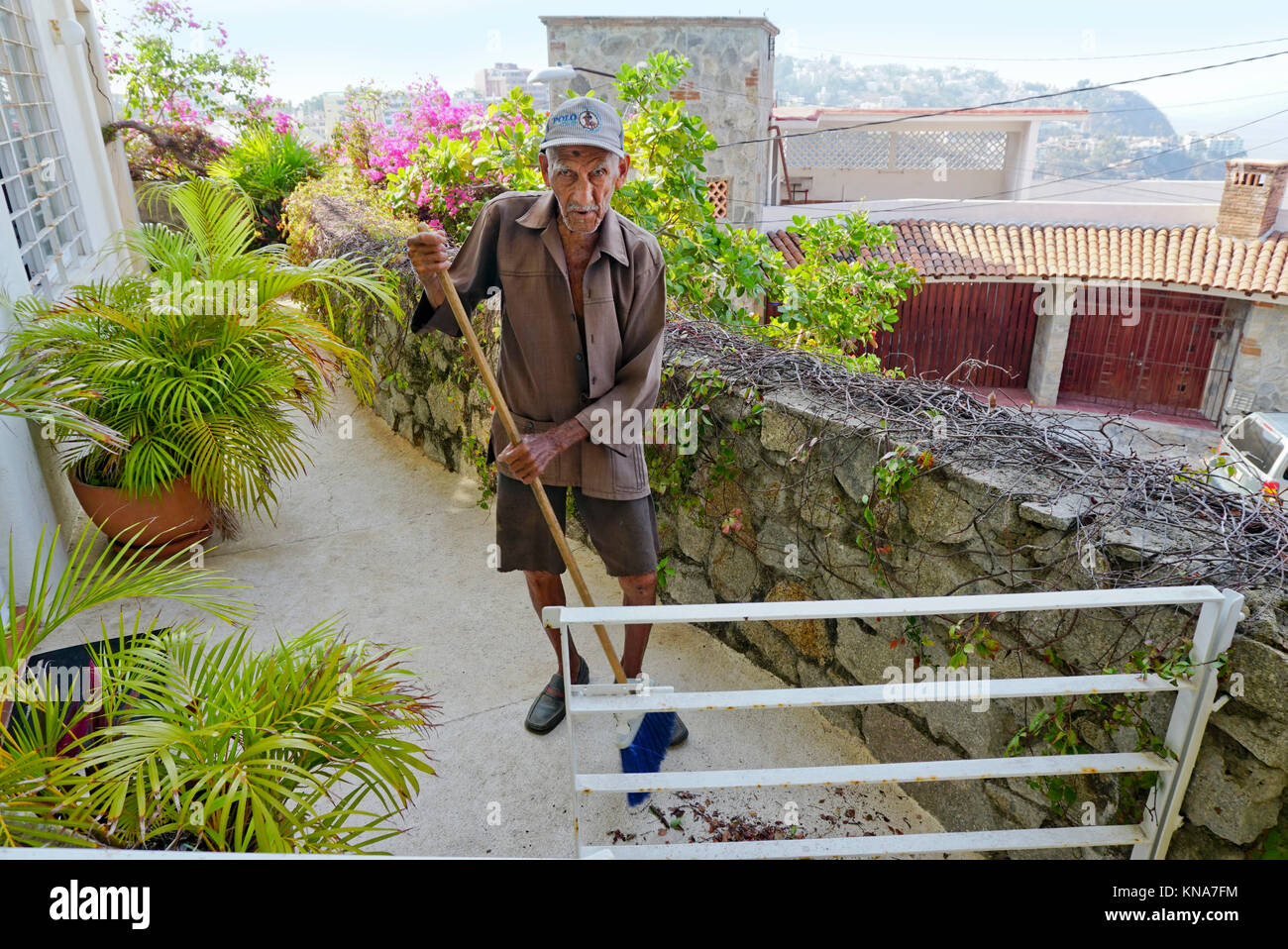 90 Jahre alte mexikanische Mann um das Haus fegt. Stockfoto