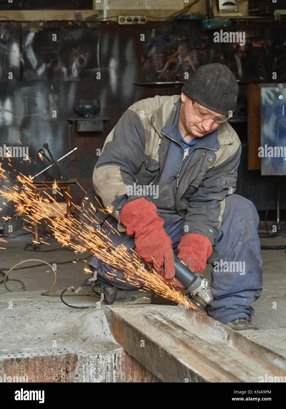 Arbeitnehmer schleift eine Metallschiene für die nachfolgende Schweißen. Das Foto zeigt die Funken von der Schleifscheibe. Stockfoto