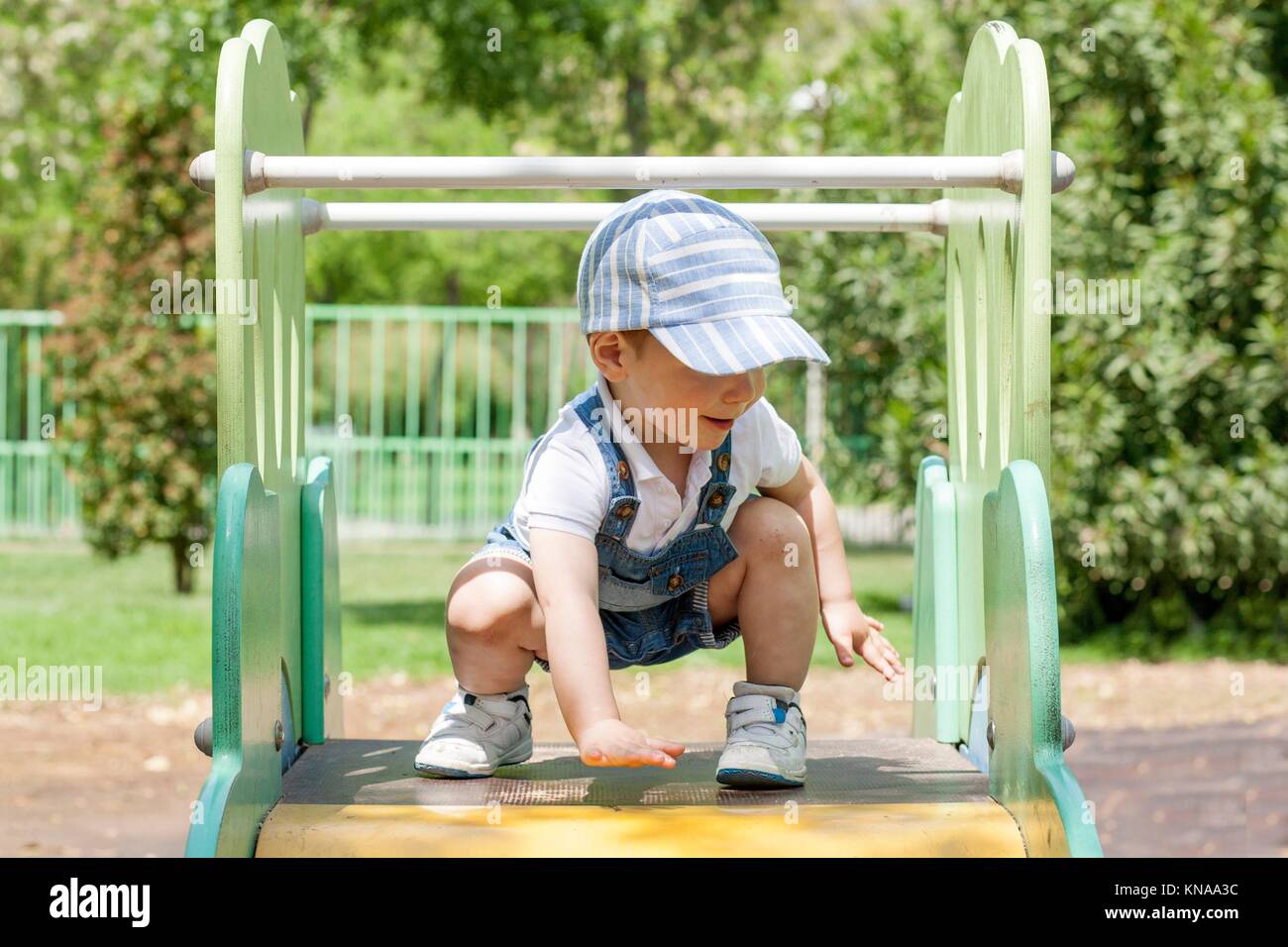 2-jähriger Junge beim Spielen auf den Schieberegler am Spielplatz. Er ist auf der Oberseite. Balance Konzept. Stockfoto
