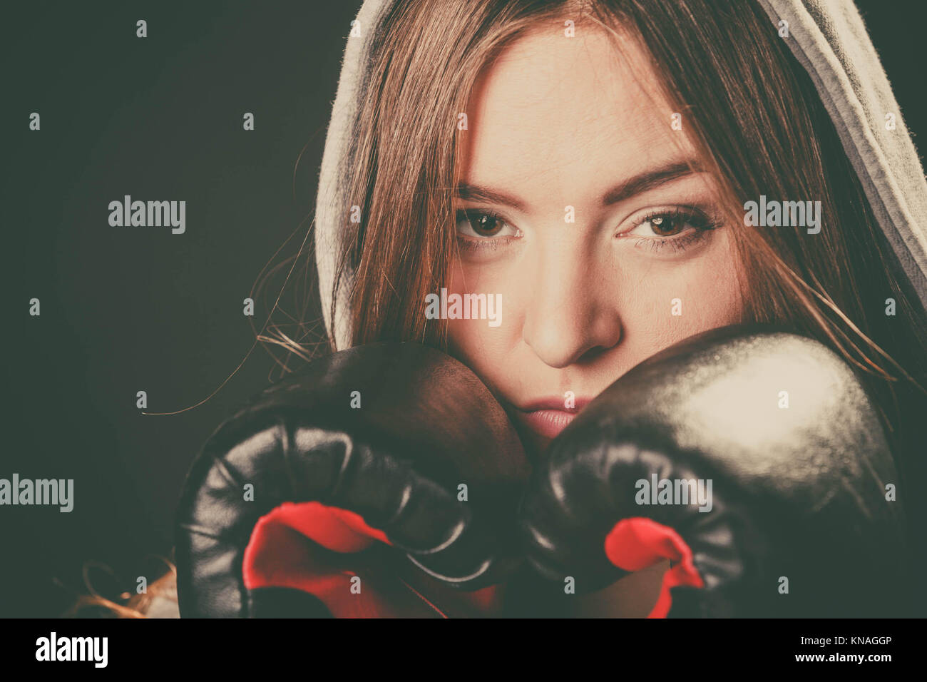 Bekämpfung von Boxen und Verteidigung. Sportlichkeit und starken Körper. Junge Frau tragen Sportswear und Boxhandschuhe Abdeckung Gesicht schauen Gegner. Stockfoto