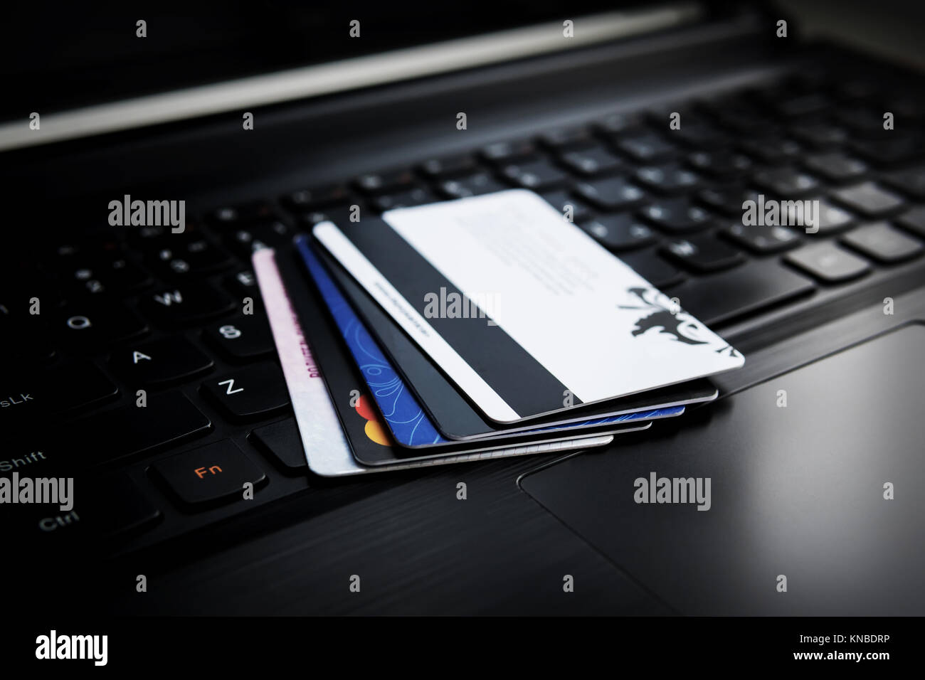 Kreditkarten auf einem Laptop. Mehrere Kredit- und Rabattkarten sind auf der Tastatur eines schwarzen Laptop. Online Zahlung. Bargeldlos. Kauf von Waren v Stockfoto
