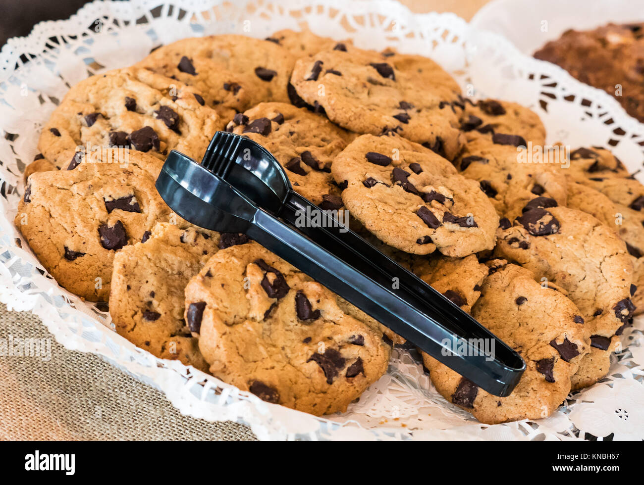Platte von Chocolate Chip Cookies mit Kunststoff Tong - Ansicht von oben. Stockfoto