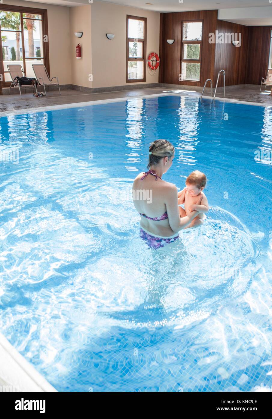 Mutter spielt mit ihrem Baby an der Schwimmbad Indoor. Kinder lernen beim Familienurlaub zu schwimmen. Stockfoto
