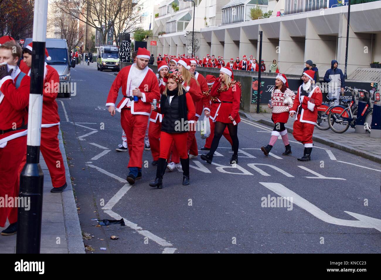 Flash Mob verkleidet als Weihnachtsmann zu Fuß durch London und tranken und waren fröhlich für Santacon 2017 im Norden von London, King's Cross Bereich Stockfoto