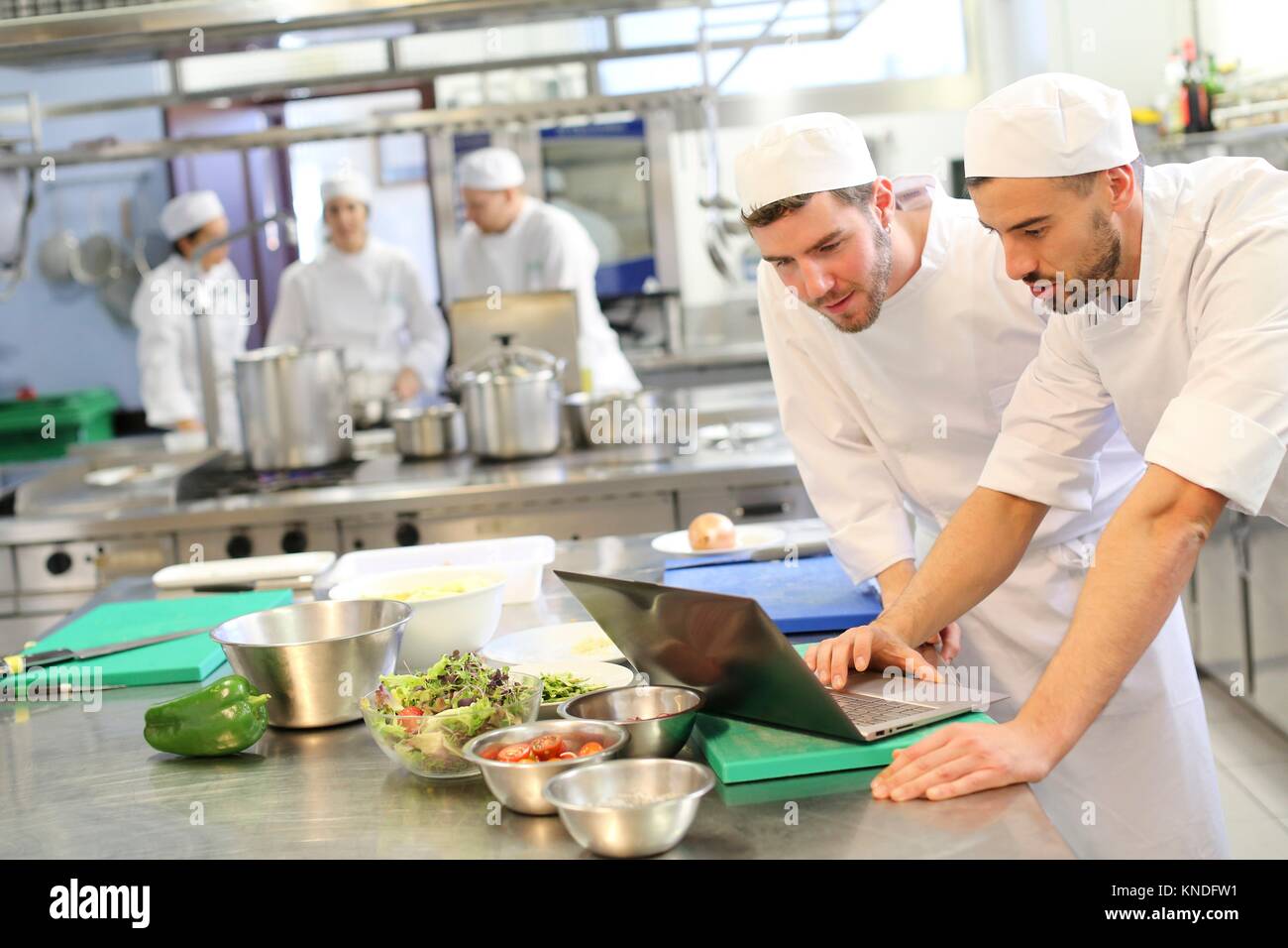 Koch mit Laptop, Kochen in der Küche der Schule, Küche