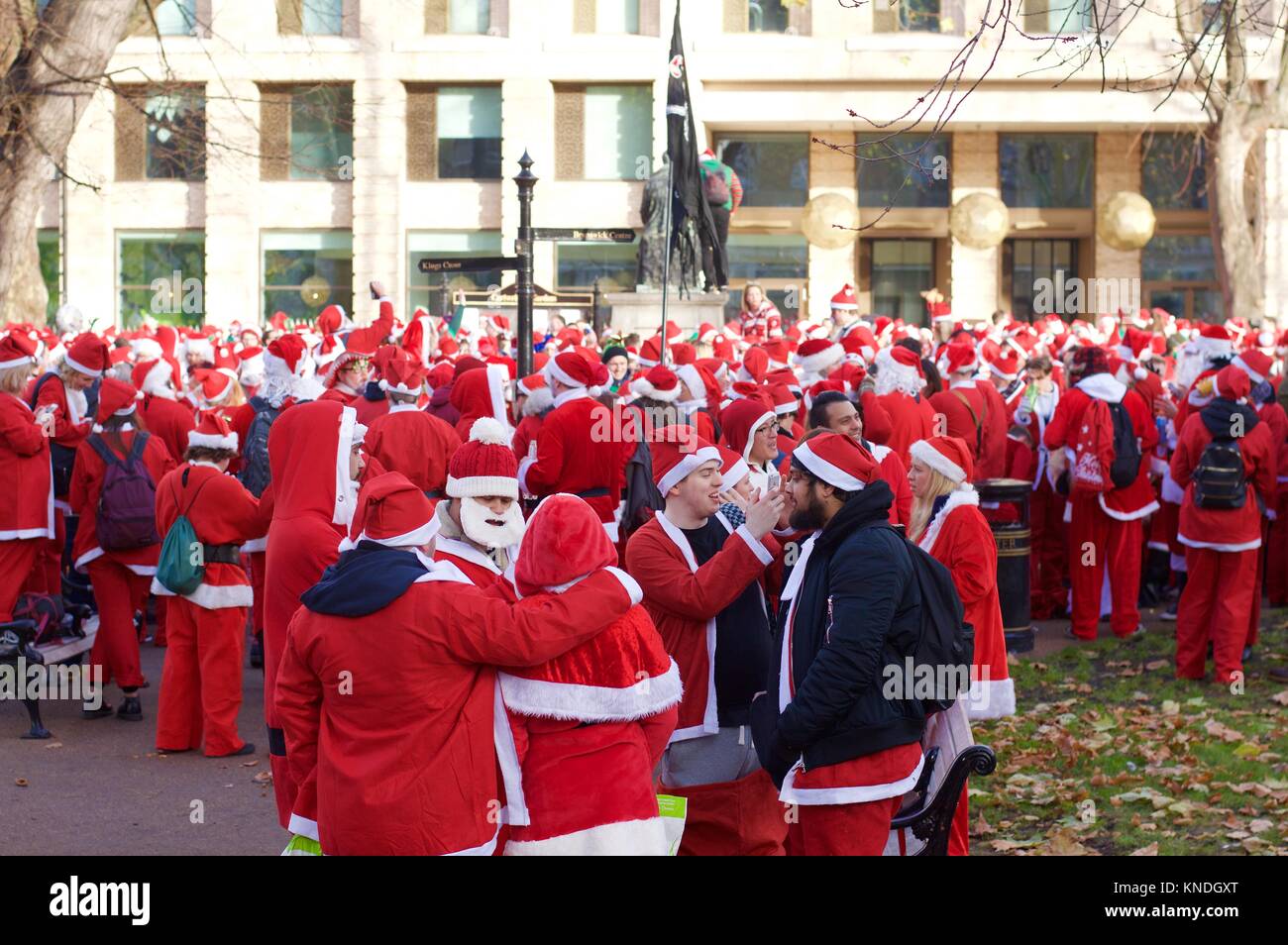 Flash Mob verkleidet als Weihnachtsmann zu Fuß durch London und tranken und waren fröhlich für Santacon 2017 im Norden von London, King's Cross Bereich Stockfoto