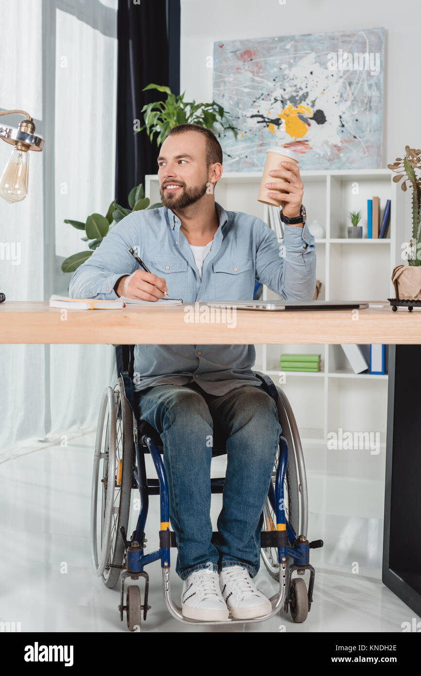 Der Mensch im Rollstuhl sitzen am Arbeitstisch Stockfoto