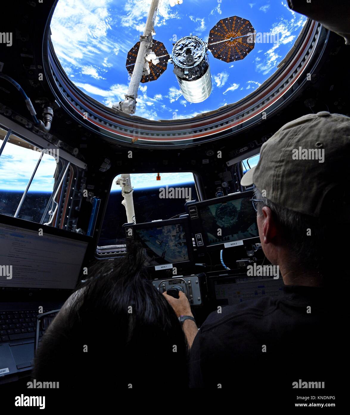 Expedition 53 amerikanische Astronaut Mark Vande Hei an den Kontrollen der robotischen Kanada Arm 2 vor der Freigabe der Orbital ATK Cygnus cargo Raumfahrzeug von der internationalen Raumstation am 6. Dezember 2017 in der Erdumlaufbahn. Cygnus eingesetzt 14 CubeSats aus dem NanoRacks Bereitsteller und wird später auf destruktive Wiedereintritt in die Atmosphäre der Erde verbrannt werden. Stockfoto