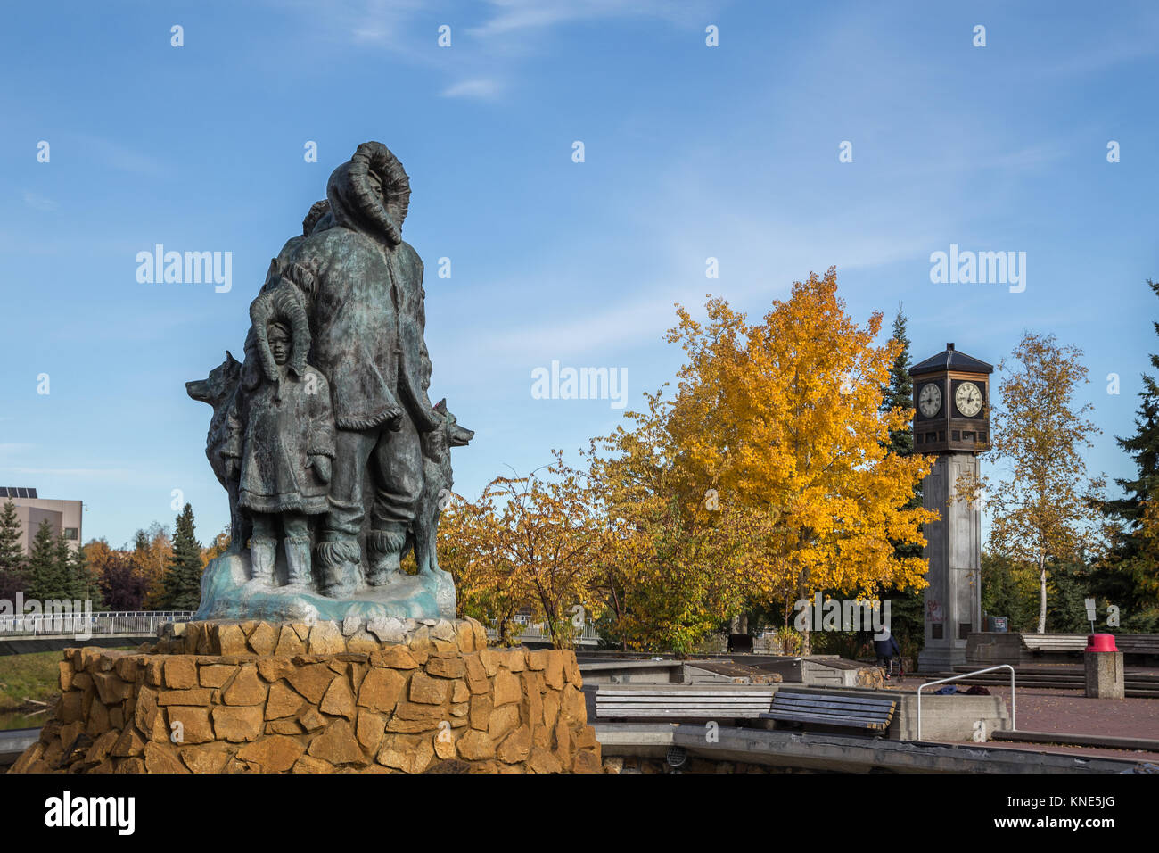 Unbekannte erste Familie Statue im goldenen Herzen Park in Fairbanks, Alaska, USA im Herbst zeigen Fairbanks Rotary 50-Uhr und Glockenspiel Stockfoto