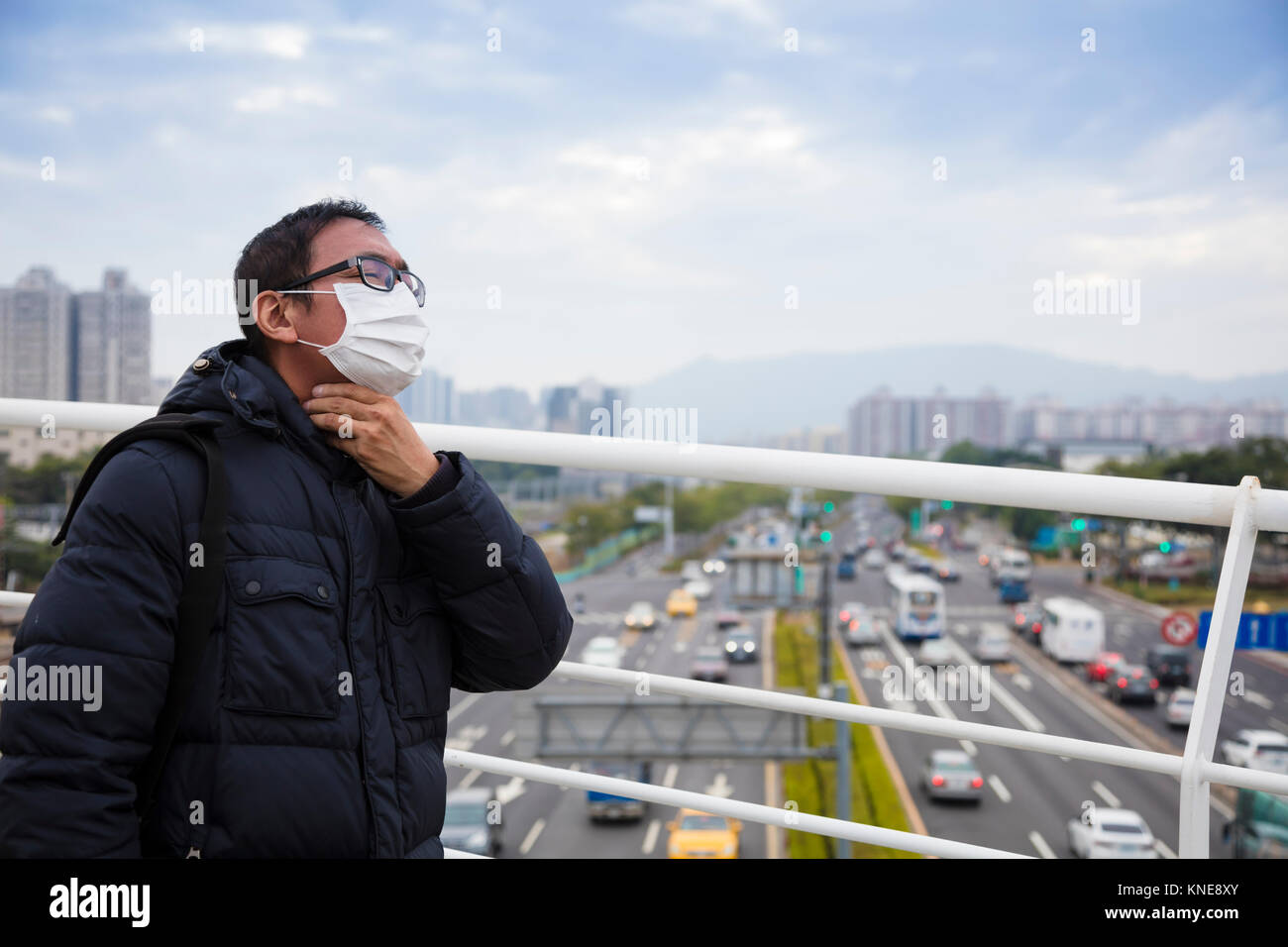 Smog in der Stadt. Männer in der medizinischen Maske mit Halsschmerzen Stockfoto