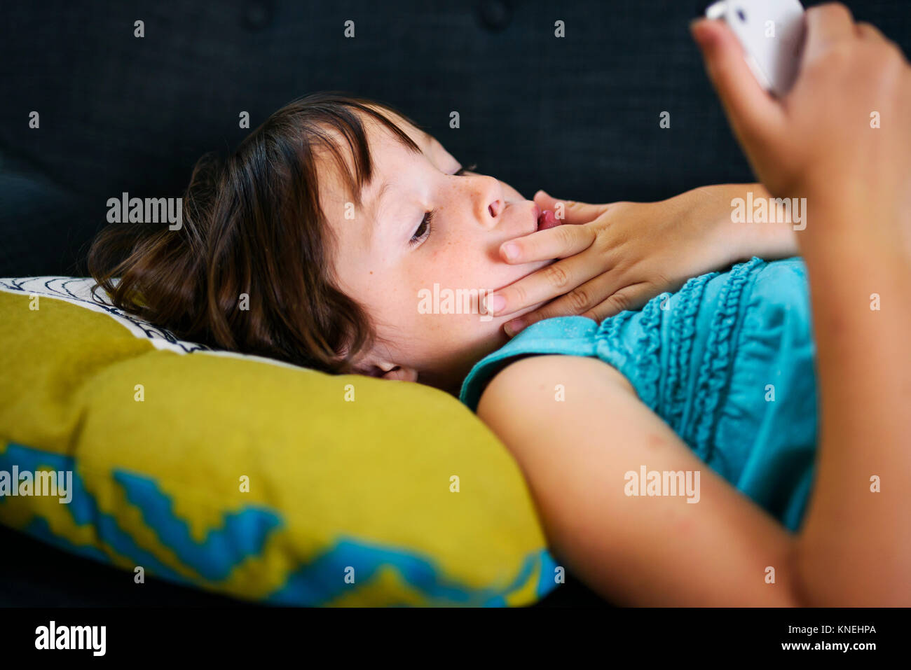 Mädchen liegt auf der Couch auf Ihrem Mobiltelefon suchen Stockfoto
