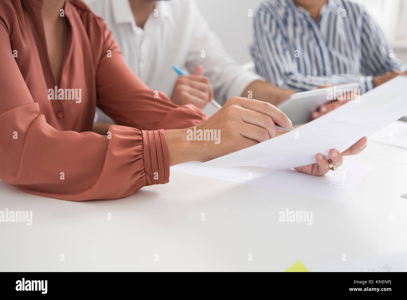 7/8 Schuß von geschäftsfrauen und Mann mit Papierkram und digitale tablet Konferenztisch Stockfoto